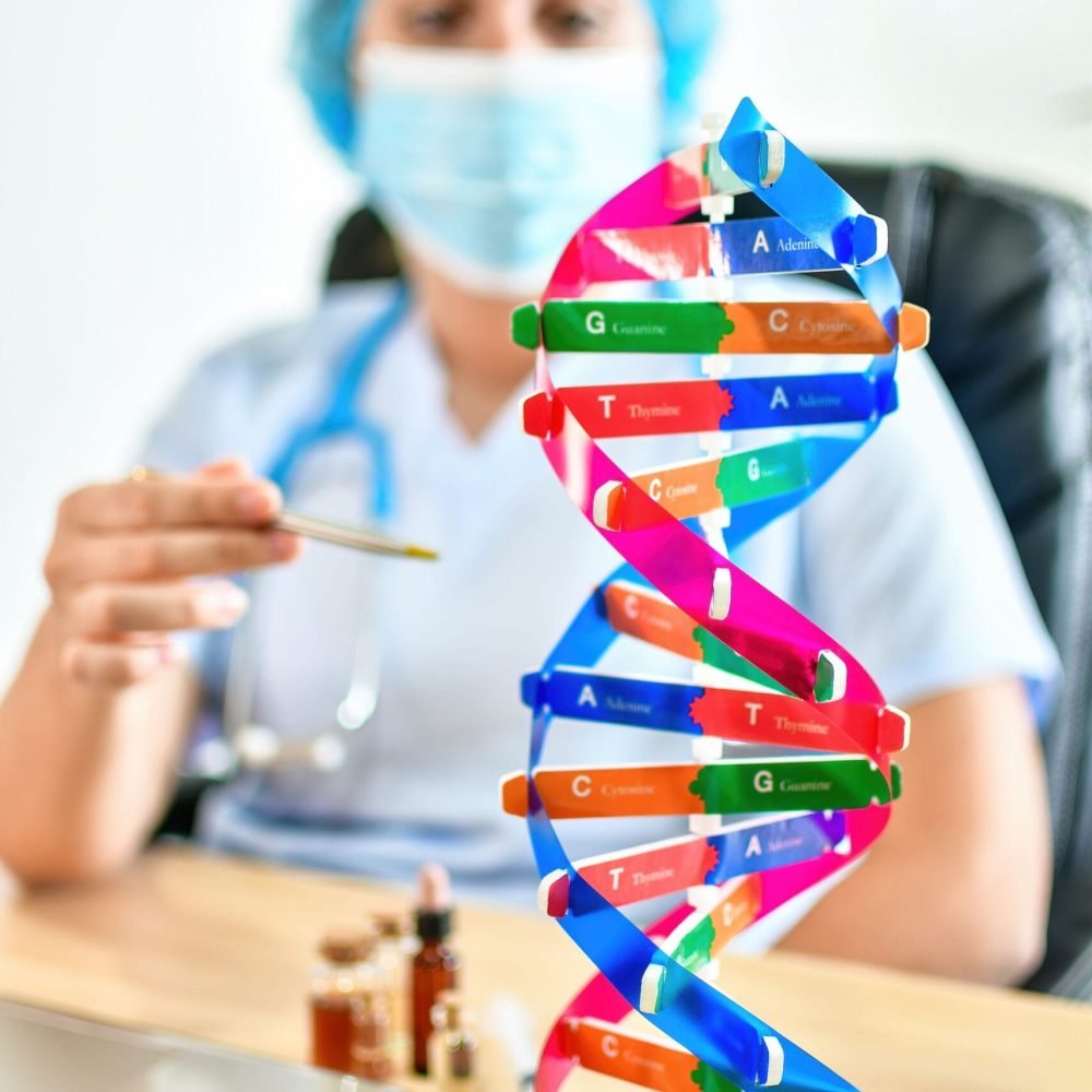 A selective focus of a doctor and a DNA model structure near laptop on desk in laboratory.