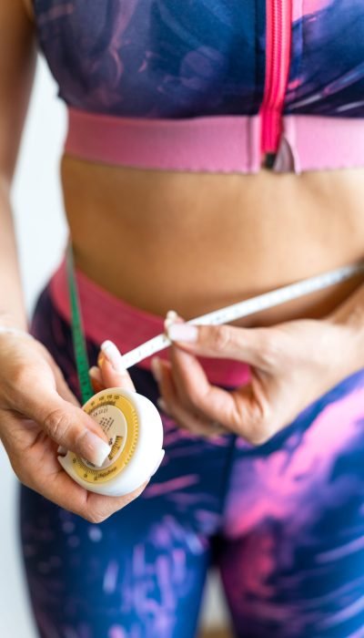 Woman measuring her waist with retractable tape measure